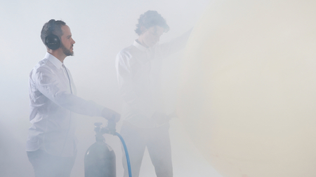 Eugene Ughetti and Mattias Schack-Arnott stand in mist, holding a pressurised air can.