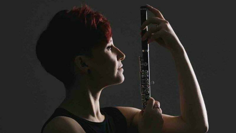 Eliza Shephard holds a flute up vertically next to her face.