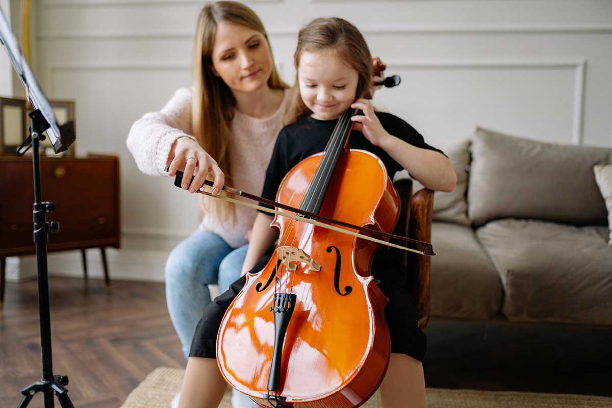 Music and Genetics: A small girl holds a cello while her mother uses the bow.