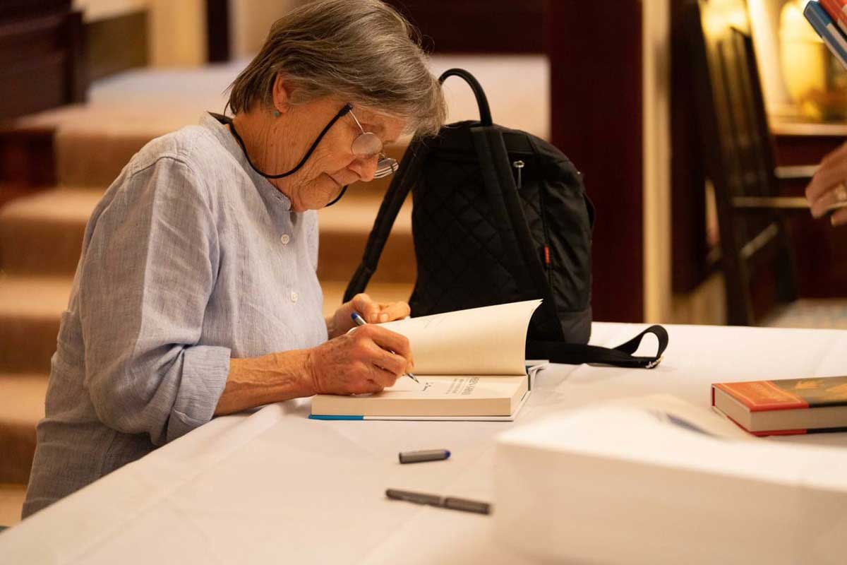 An author signs the inner cover of her book at a table for a fan.