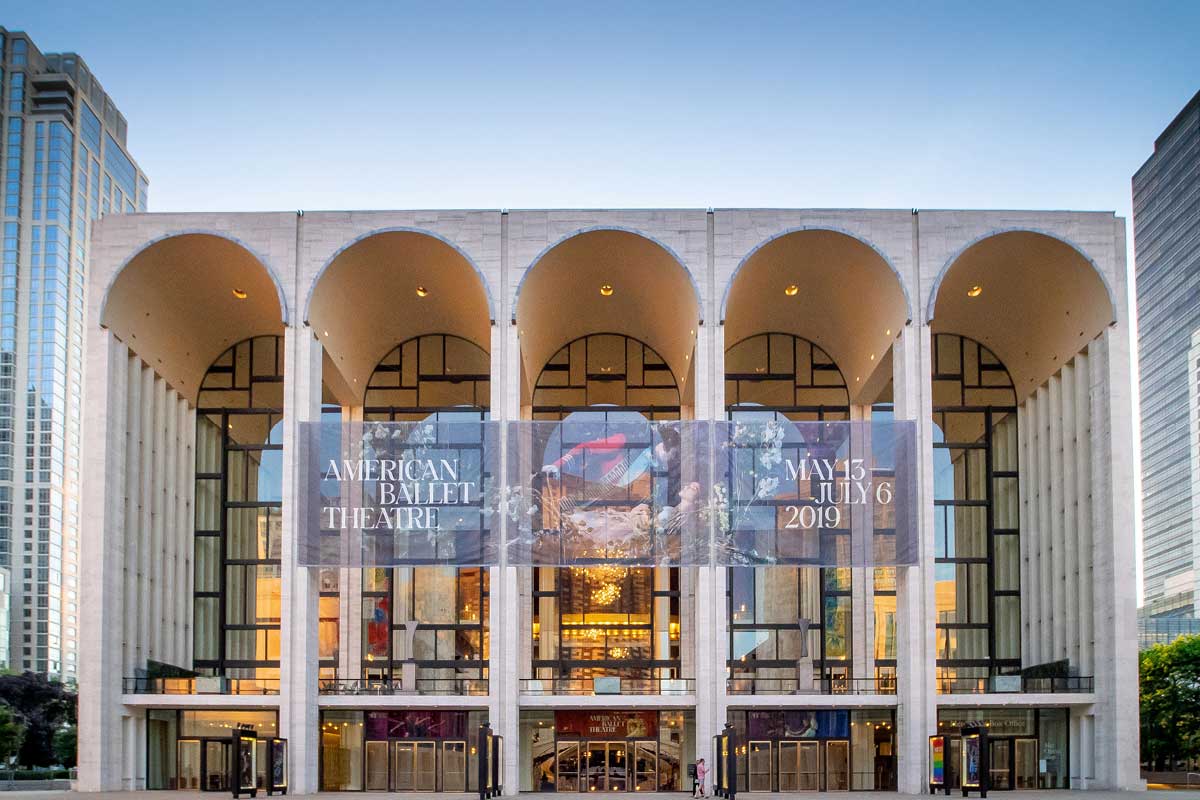 The arched front of the Metropolitan Opera House, with a banner out the front advertising the 2019 season of the American Ballet Theatre.