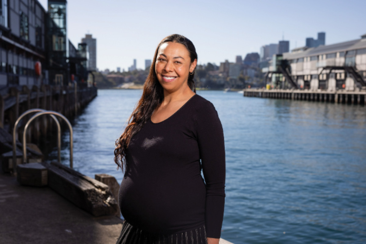 Jasmin Sheppard stands in front of the water at the Walsh Bay piers. She is pregnant.
