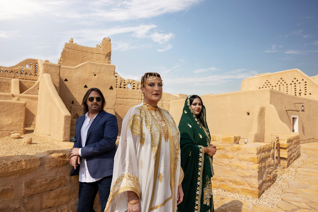 Lee Bradshaw, Dame Sarah Connolly and Reemaz Oqbi stand in front of buildings in Saudi Arabia.