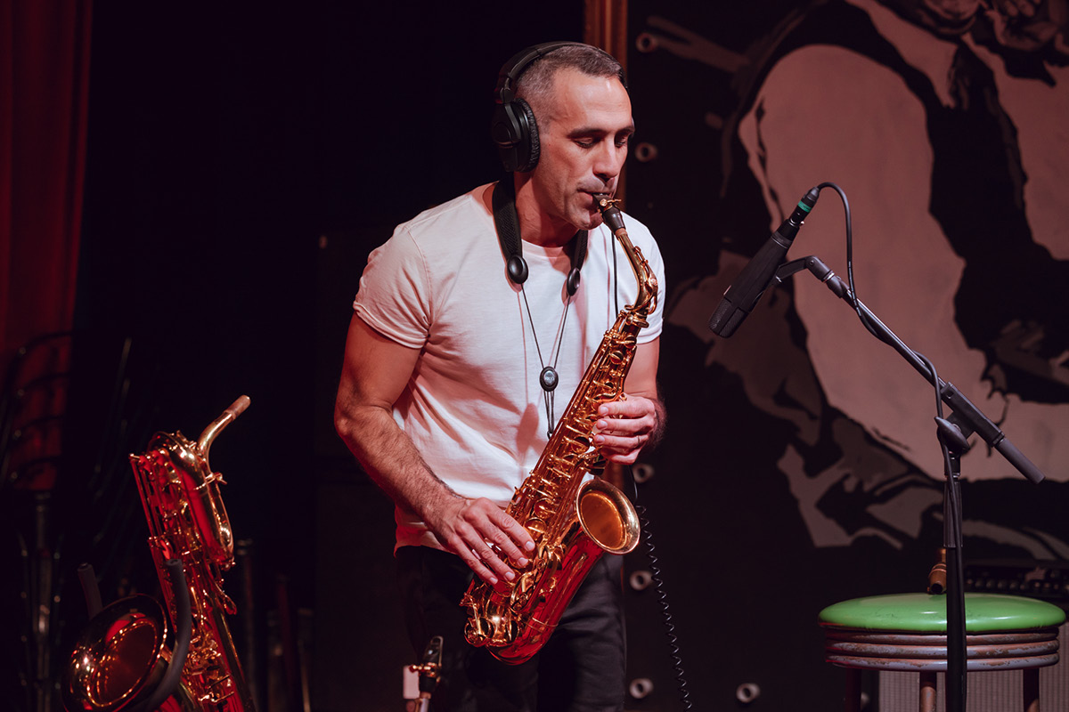 Nick Russoniello performing on alto sax with headphones on.