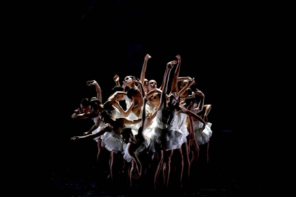 Ballet Preljocaj dancers form a group and sway their arms, giving the appearance of a swan.