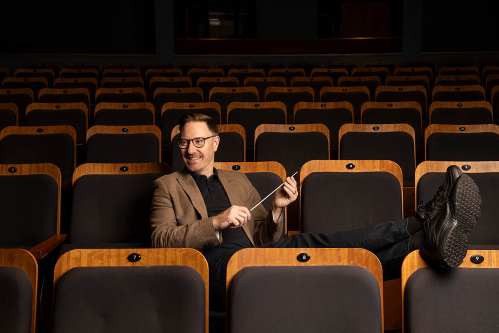 Benjamin Northey sits in audience chairs, his feet up, at the Sydney Conservatorium's Recital Hall.