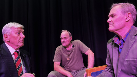 Three men sitting on stage