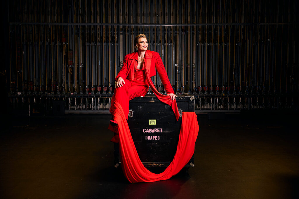 Reuben Kaye sits on a road case labelled 'cabaret drapes' backstage.